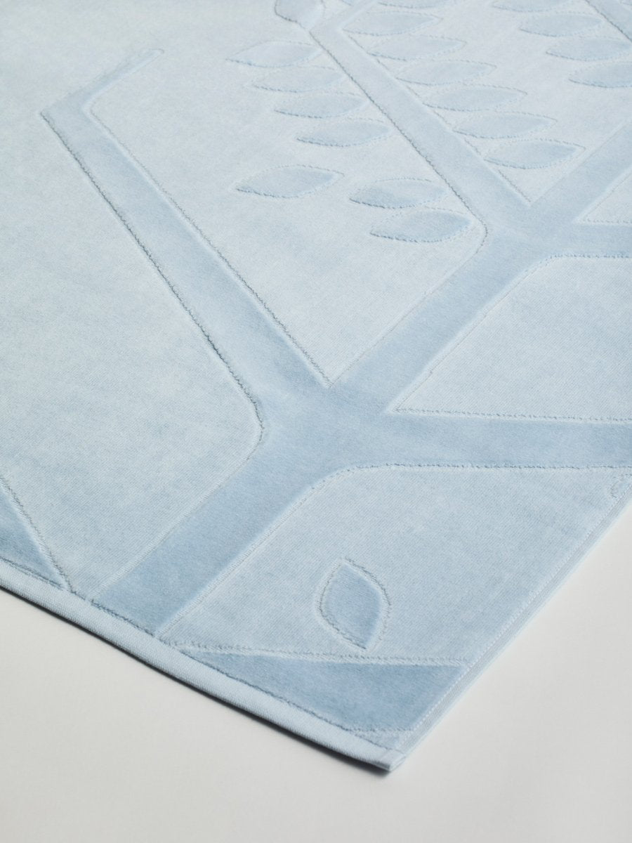 Close-up of a 'Maldivian Atoll' beach towel with a textured and embossed Four Seasons logo design. - {{Maldivian Atoll}}