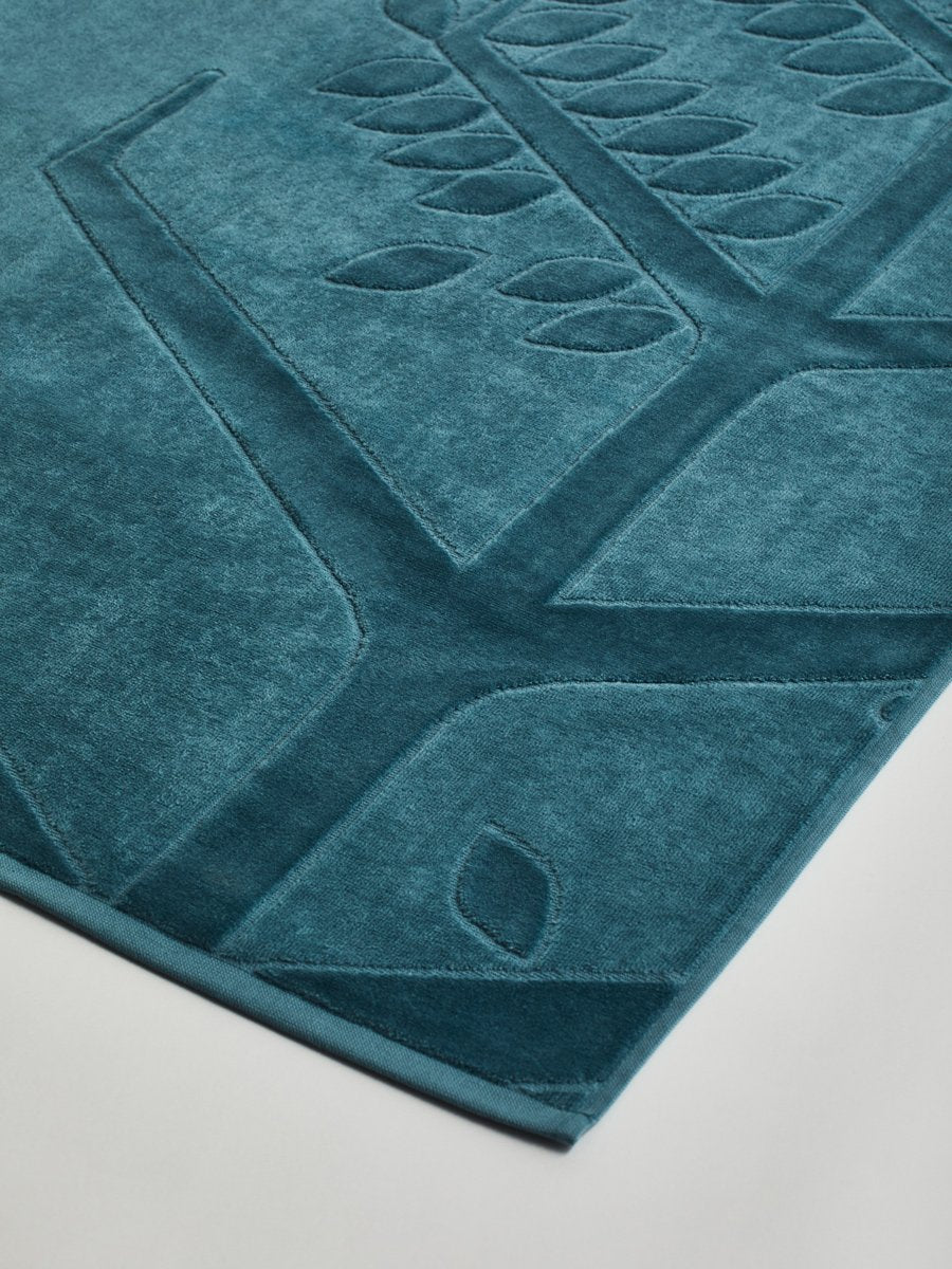 Close-up of a 'Polynesian Lagoon' beach towel with a textured and embossed Four Seasons logo design. - {{Polynesian Lagoon}}