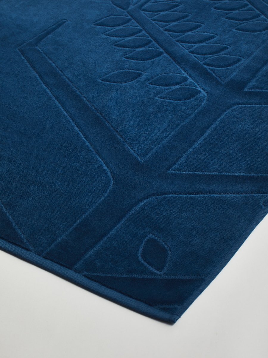Close-up of a 'Riviera Navy' beach towel with a textured and embossed Four Seasons logo design. - {{Caribbean Seascape}}