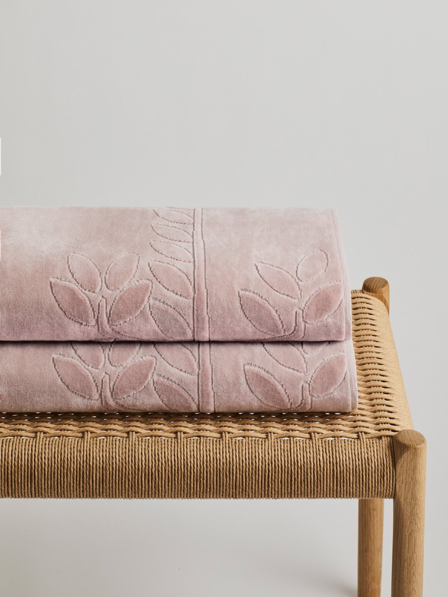 Two 'Hawaiian Sunrise' beach towels folded on a wooden bench. The towels feature a subtle leaf pattern. - {{Hawaiian Sunrise}}