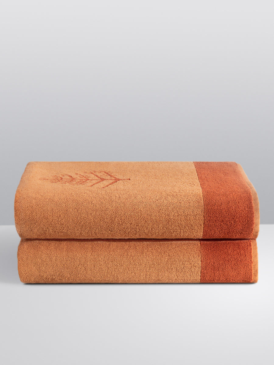 Two folded Resort Towels in an "Arabian Terracotta" color, featuring an embroidered Four Seasons logo. The towels are stacked on a white surface. - {{Arabian Terracota}}