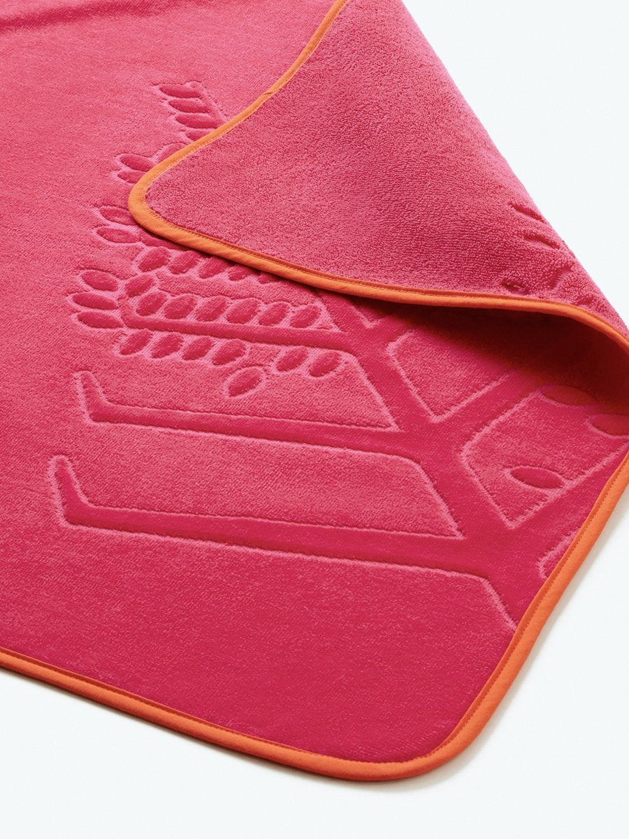 Close-up detail of a "Coral Reef Pink" hooded baby towel with a textured, embroidered Four Seasons logo. - {{Coral Reef Pink / Mountain Grey}}