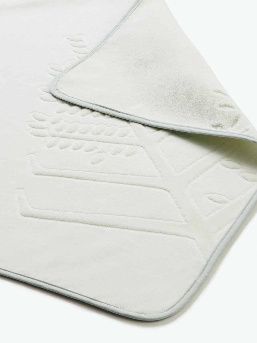 Close-up detail of a "Safari Sage" hooded baby towel with a textured, embroidered Four Seasons logo. - {{Safari Sage / Mountain Grey}}