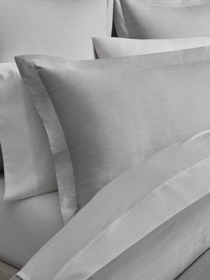 White pillowcase with thin gray stripes on a Turkish Silver/Signature White colored duvet cover. - {{Turkish Silver/Signature White}}