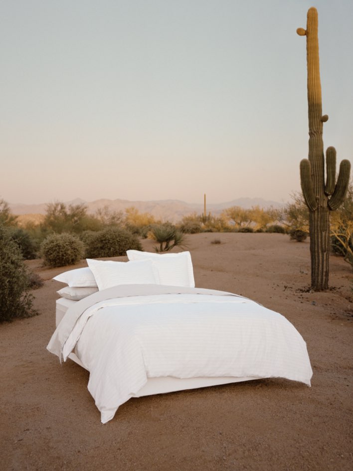 Bed dressed with white sheets and a duvet, with several pillows carefully arranged. - {{Turkish Silver/Signature White}}