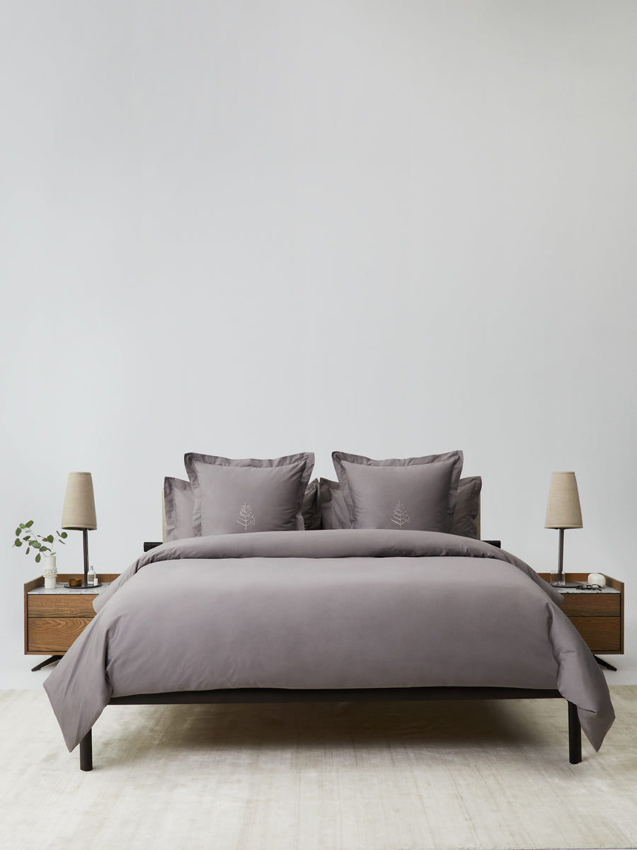 Bed dressed in a Hampshire Charcoal duvet cover set; bordered shams with tone-on-tone logo store; minimalist nightstands and lamps. {{Hampshire Charcoal}}