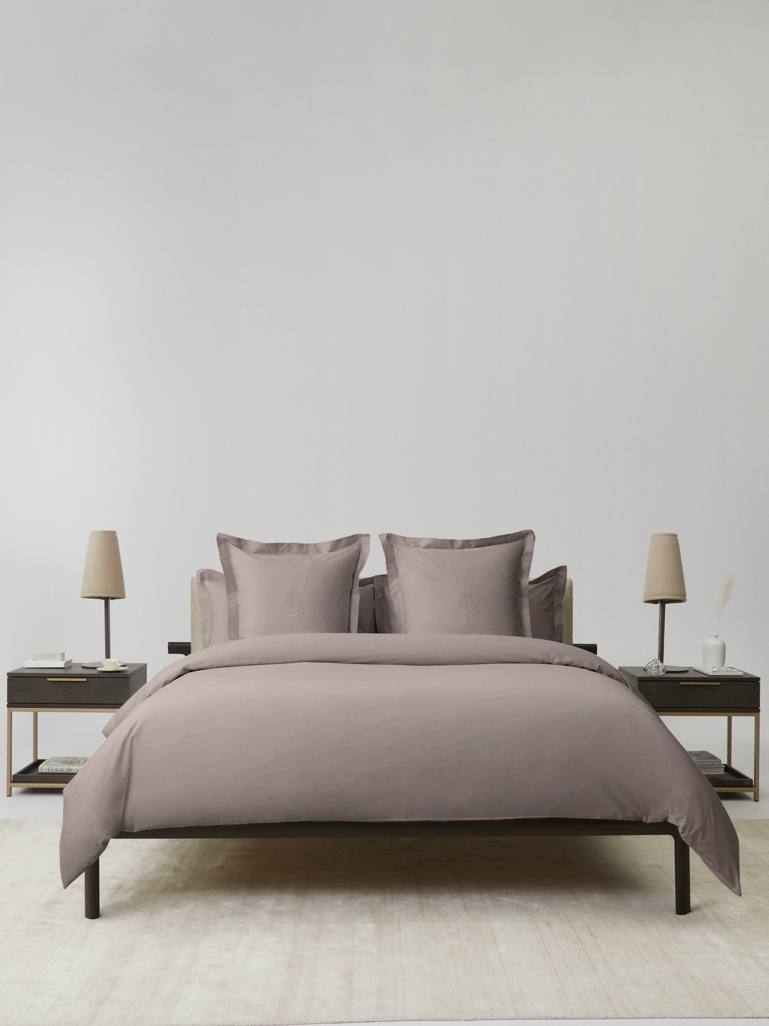 Front view of bed dressed in taupe duvet set with matching euro shams, nightstands and lamps on both sides in a minimalist bedroom. {{Moroccan Sand}}