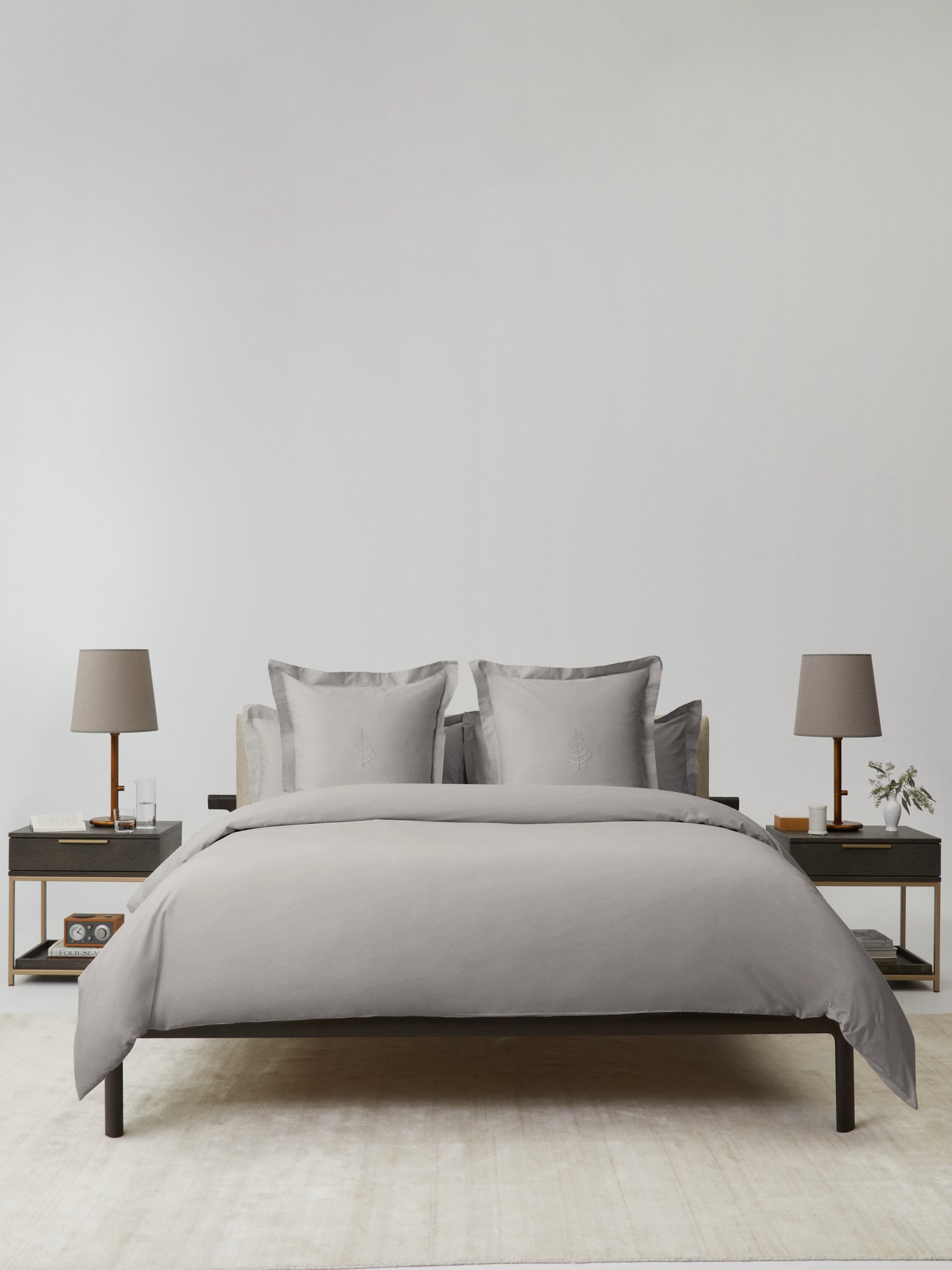 Bed dressed in a Spanish Slate duvet cover set; bordered shams with tone-on-tone logo store; minimalist nightstands and lamps. {{Spanish Slate}}