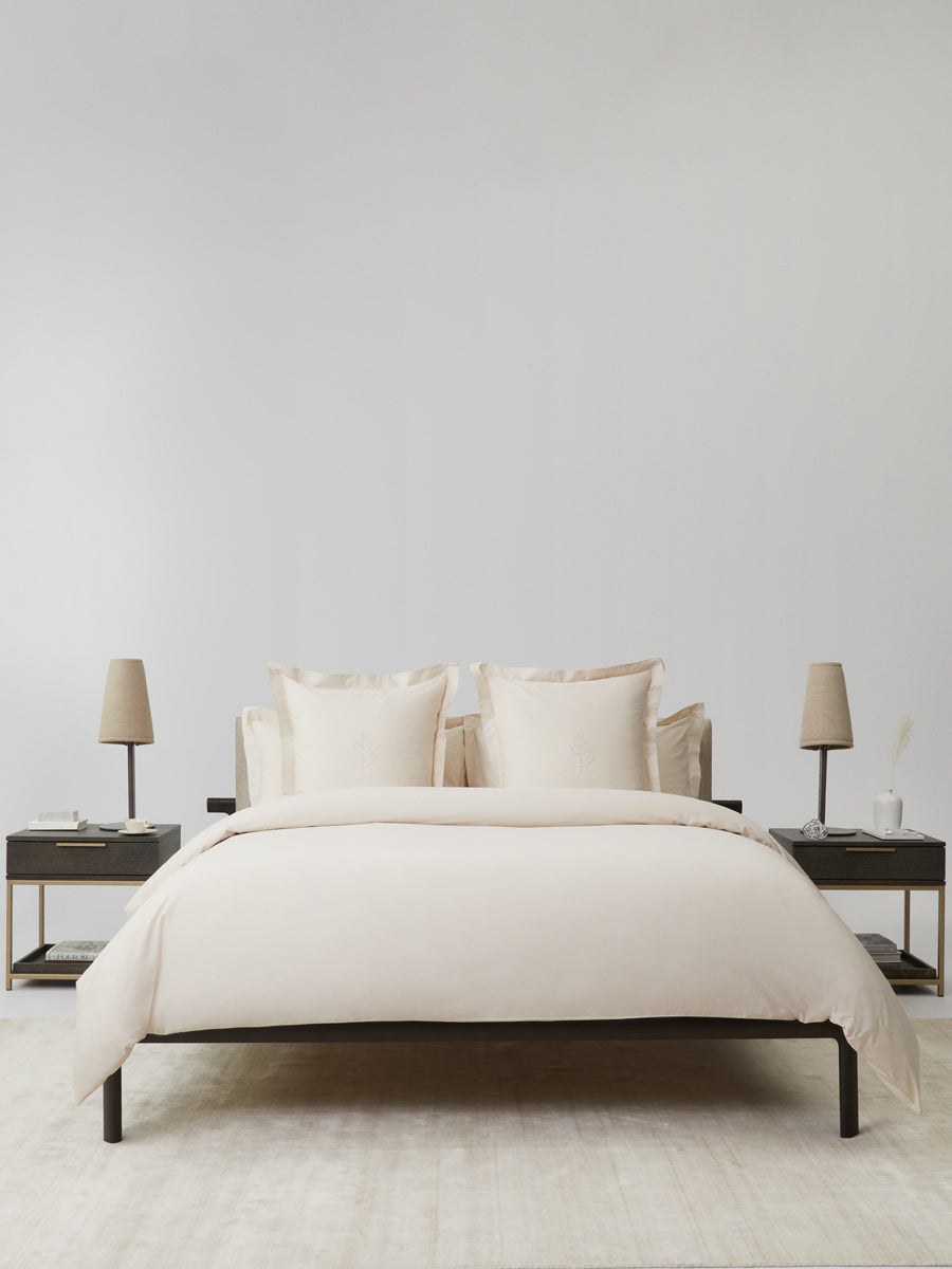 Bed dressed in a Balinese Pearl duvet cover set; bordered shams with tone-on-tone logo store; minimalist nightstands and lamps {{Balinese Pearl}}