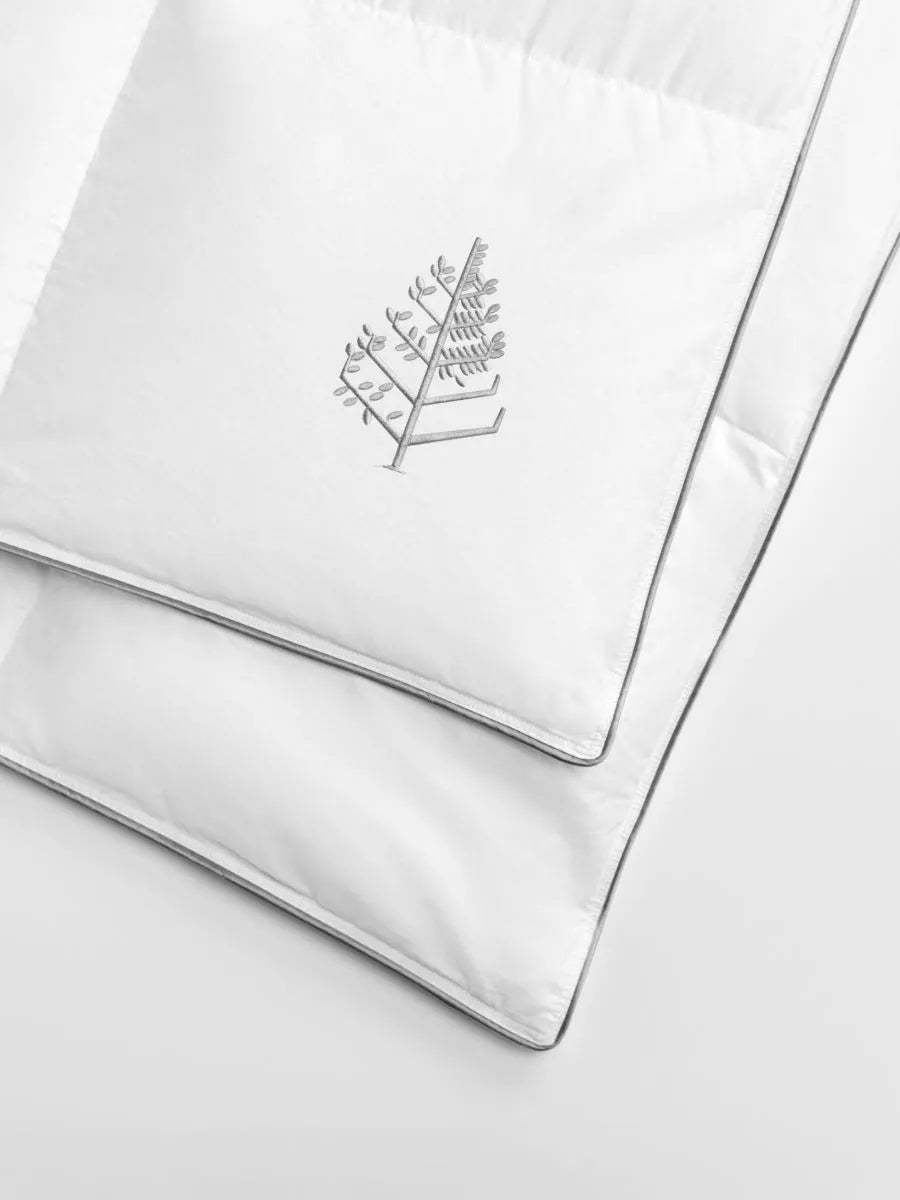 Corner of a white duvet with a Four Seasons embroidered logo.