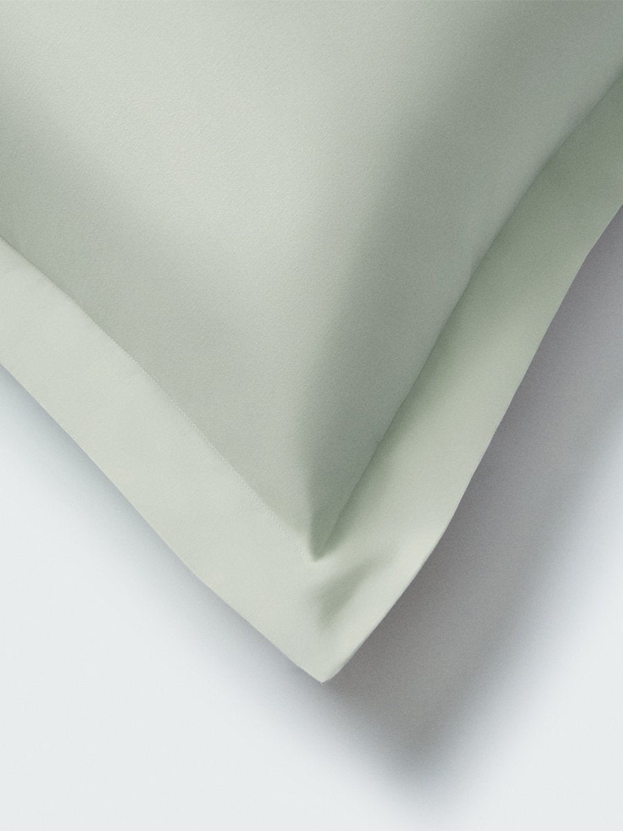 Part of a pillow with a Florentine Sage color pillowcase featuring embroidery along the edge. - {{Florentine Sage}}