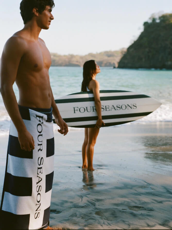 Two people with Four Seasons branded towels and a surfboard on a beach. -{{Maritime Navy}}