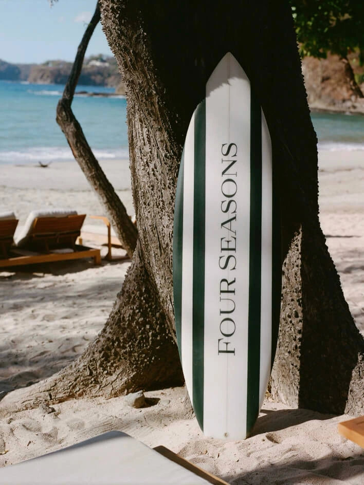 Surfboard with 'Four Seasons' branding on a beach setting - {{Maritime Navy}}