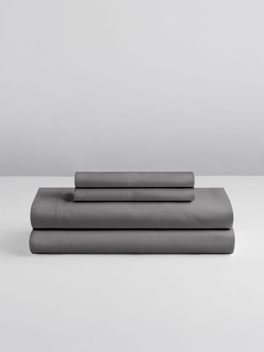 Stacked sheet set in Hampshire Charcoal showing fitted sheet, flat sheet, and two pillowcases. {{Hampshire Charcoal}}