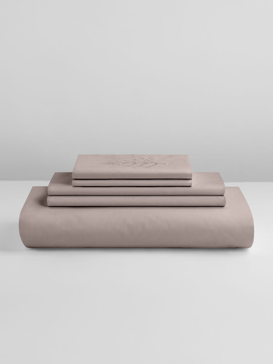 Product stack of Moroccan Sand duvet cover set—folded duvet cover, matching shams, and embroidered piece—on a white background. {{Moroccan Sand}}