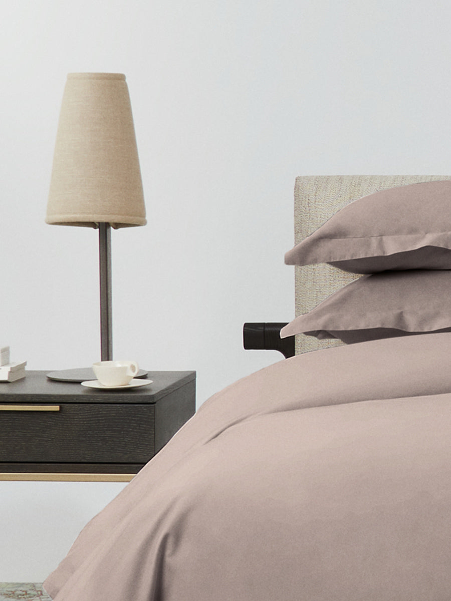 Side view of bed dressed in Moroccan Sand duvet set with matching pillow shams beside a nightstand and lamp. {{Moroccan Sand}}
