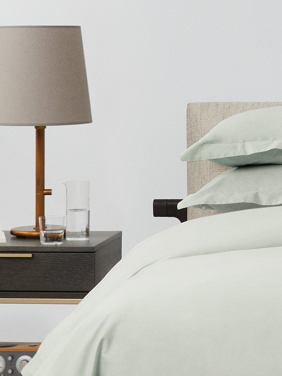 Bed dressed with a duvet in Florentine Sage color and two pillows with embroidery along the edge. - {{Florentine Sage}}