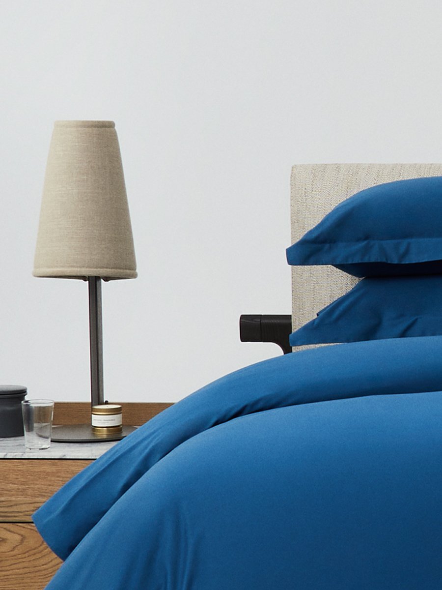Bed dressed with a duvet in Riviera Navy color and two pillows with embroidery along the edge. - {{Riviera Navy}}