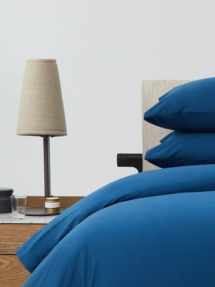 Bed dressed with a duvet in Riviera Navy color and two matching pillows. - {{Riviera Navy}}