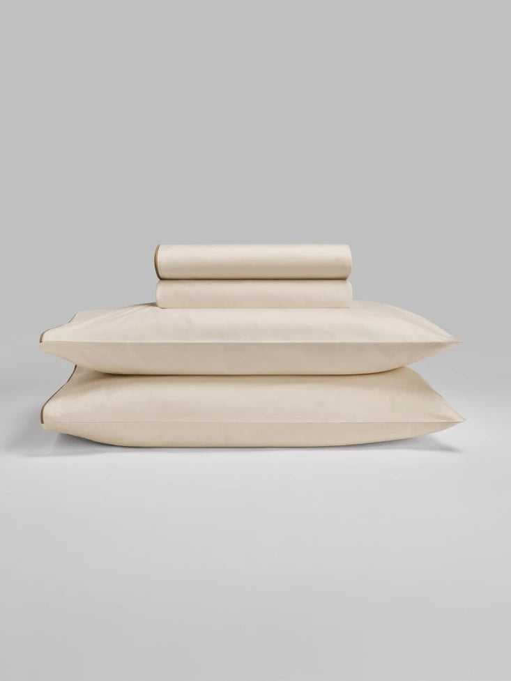 Sycamore Sheet Set in Balinese Pearl— folded fitted and flat sheets stacked over matching pillowcases. - {{Balinese Pearl}}