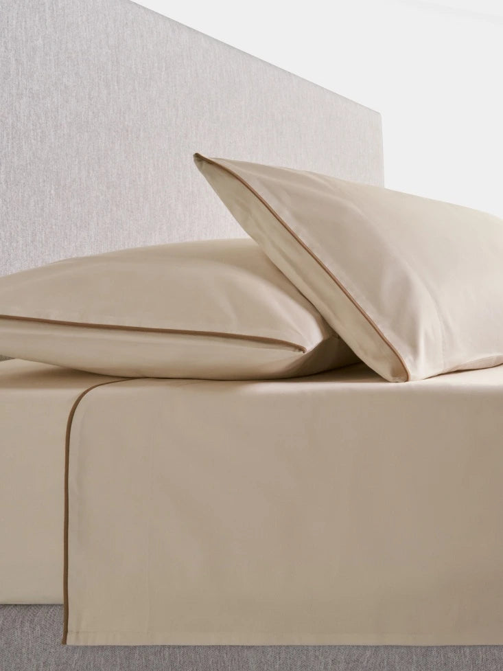 Sycamore Sheet Set in Balinese Pearl —flat and fitted sheet with modern piped hem, styled on bed with matching pillowcases. - {{Balinese Pearl}}
