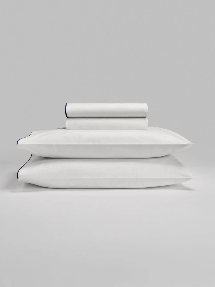 Sycamore Sheet Set in Signature White — folded fitted and flat sheets stacked over matching pillowcases. - {{Signature White}}