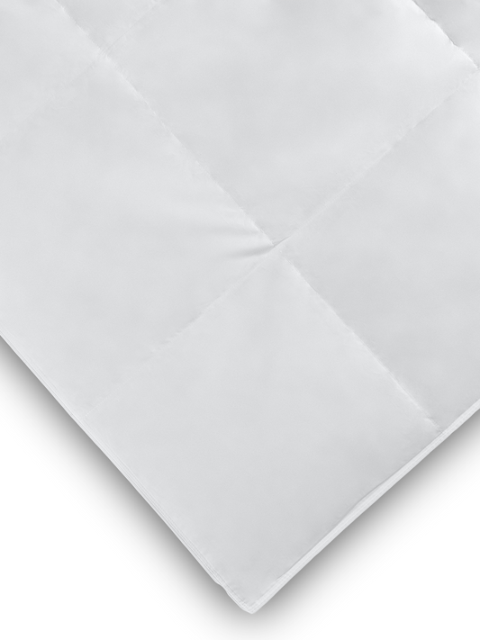 Close-up of the corner of a white lightweight comforter showing its quilted pattern and soft texture.