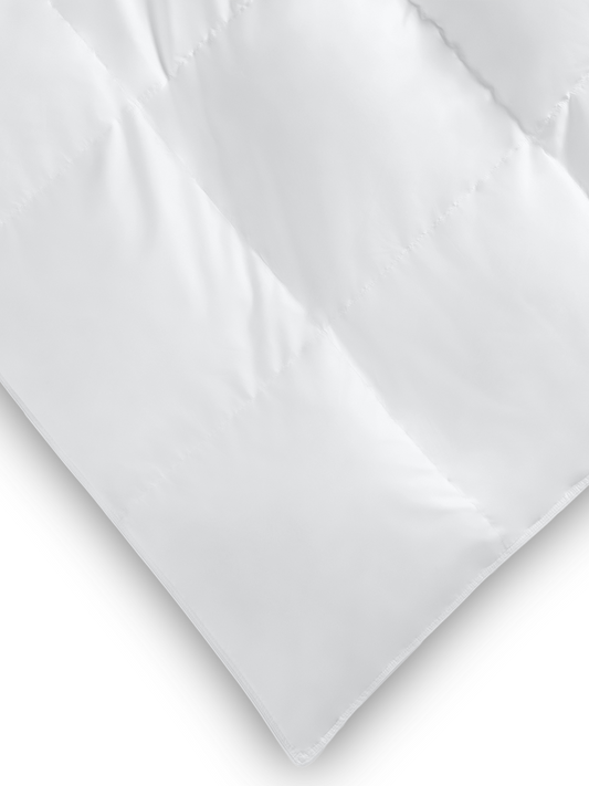 Close-up of the corner of a white down alternative comforter showing its quilted pattern and soft texture.