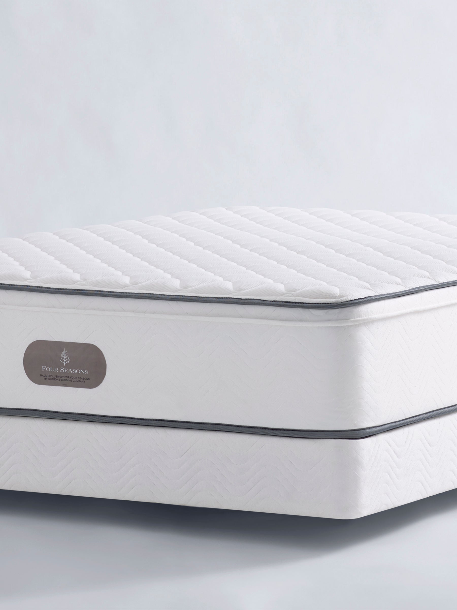 Four Seasons Signature Firm Mattress. White mattress with a quilted top and a box spring.