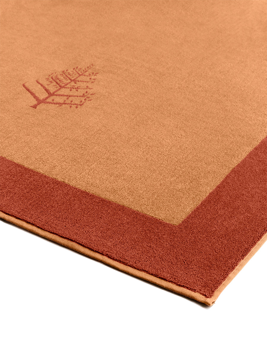 Close-up of a "Arabian Terracotta" Resort Towel with a subtle embroidered Four Seasons logo. The towel features a darker border.