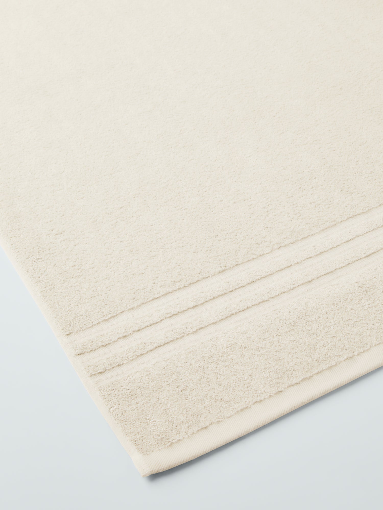 plush, folded bath sheets in a warm, inviting "Balinese Pearl" color. The towels have a thick, textured weave and subtle stripes - {{Balinese Pearl}}