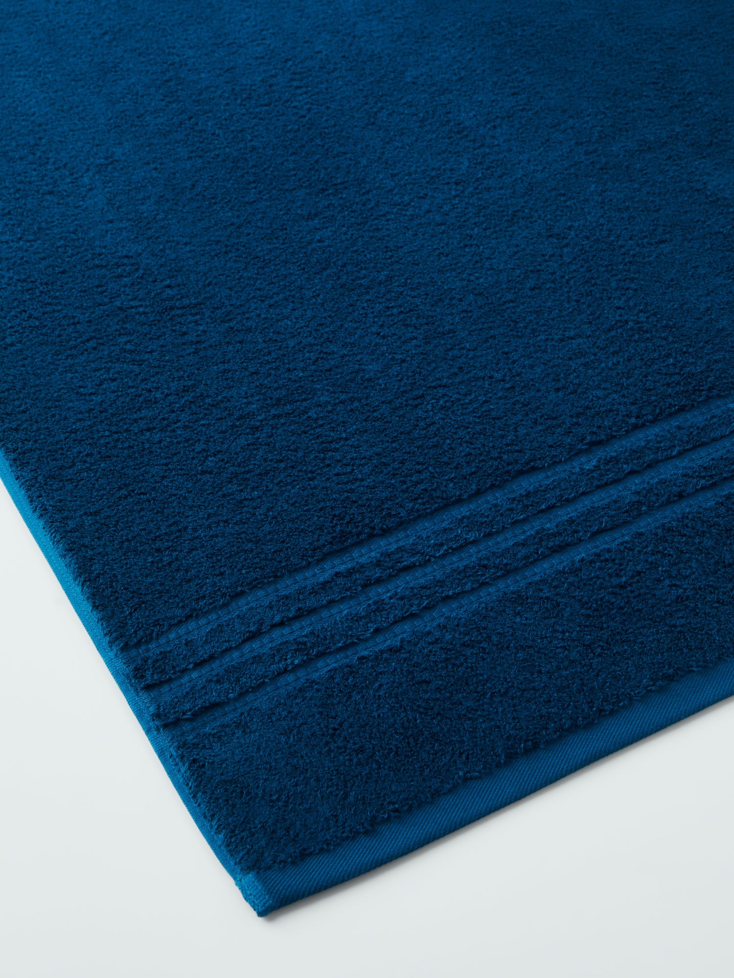plush, folded bath sheets in a warm, inviting "Riviera Navy" color. The towels have a thick, textured weave and subtle stripes - {{Riviera Navy}}