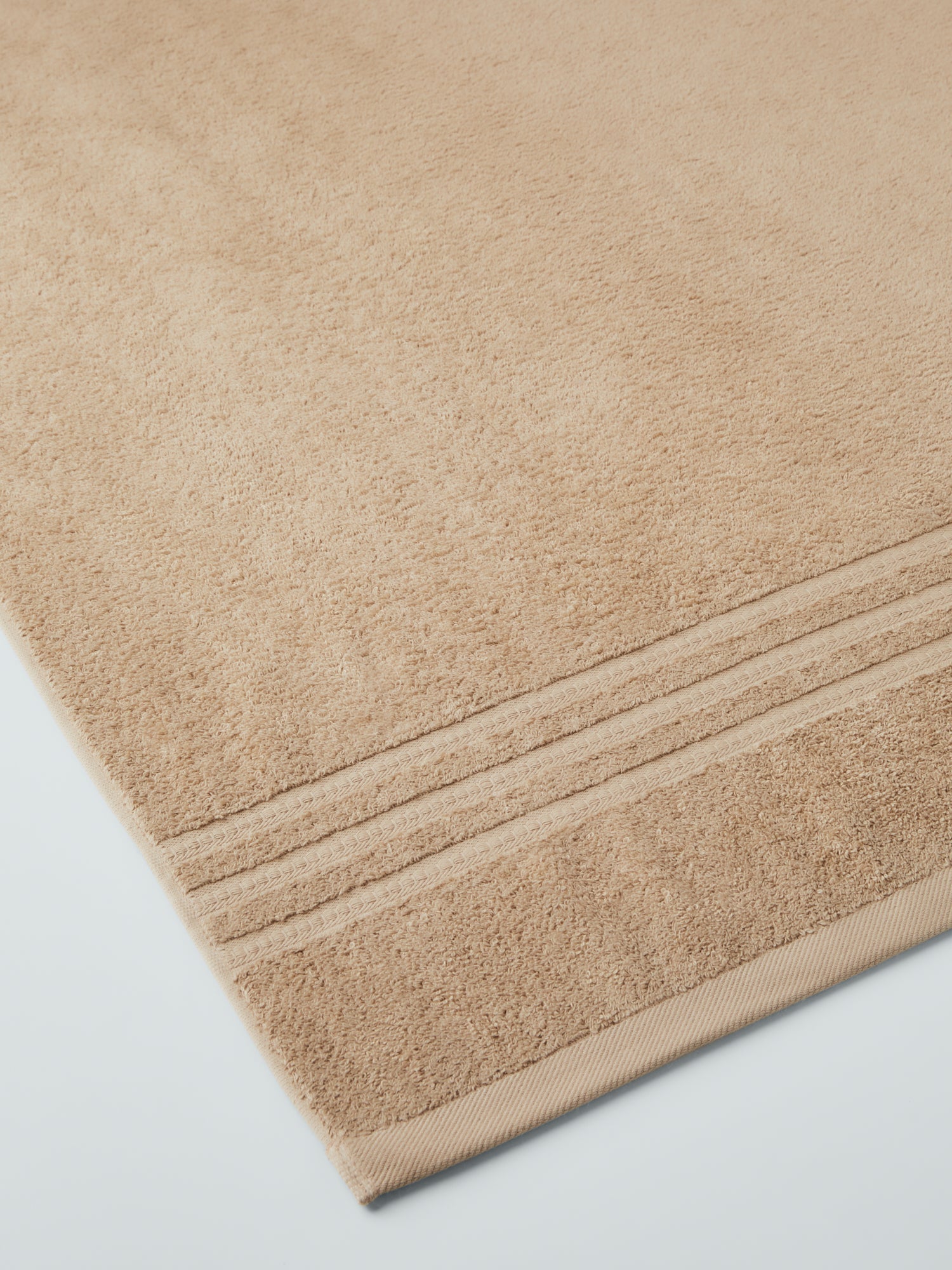 plush, folded bath sheets in a warm, inviting "Egyptian Camel" color. The towels have a thick, textured weave and subtle stripes - {{Egyptian Camel}}