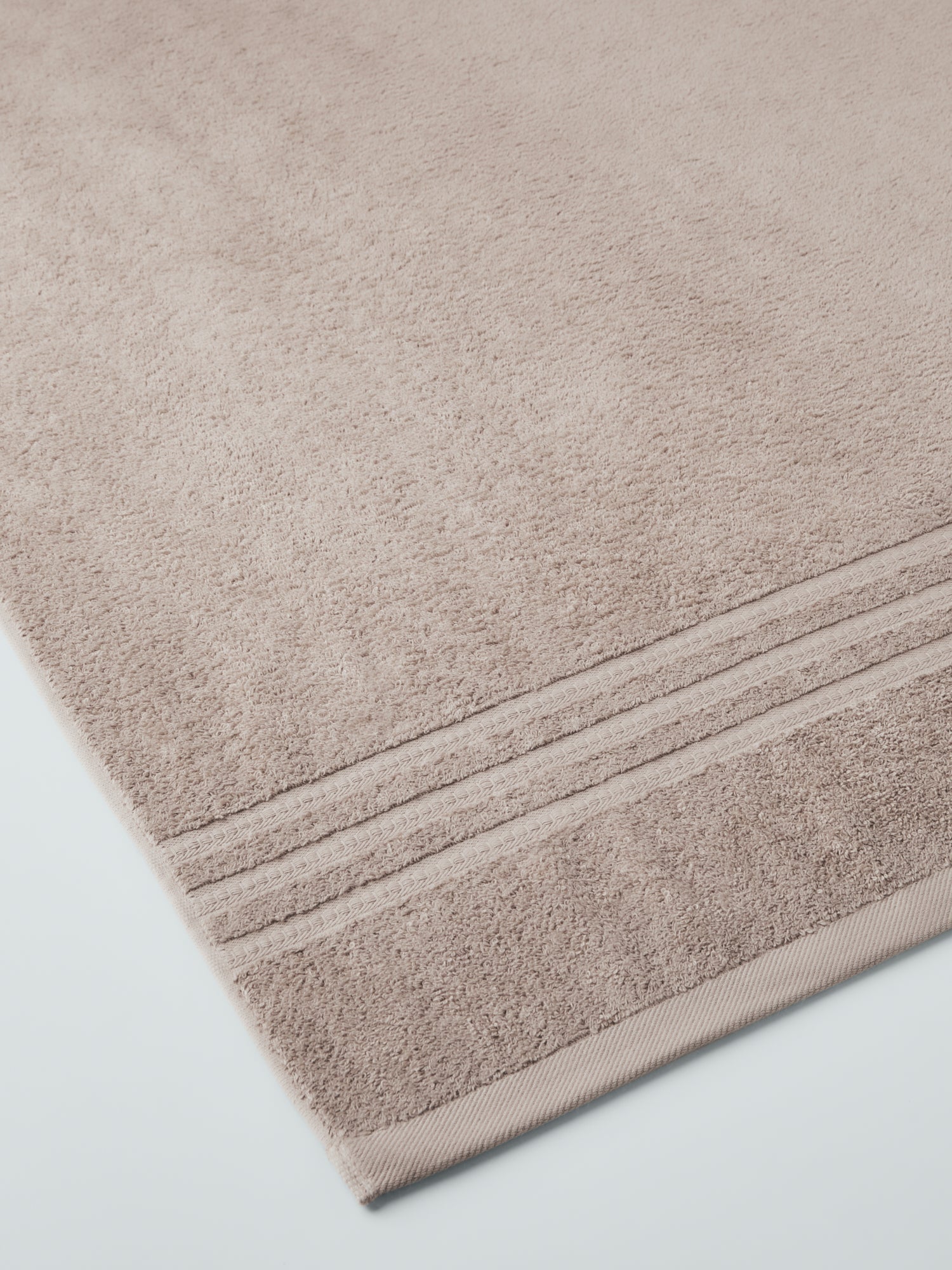 plush, folded bath sheets in a warm, inviting "Moroccan Sand" color. The towels have a thick, textured weave and subtle stripes - {{Moroccan Sand}}