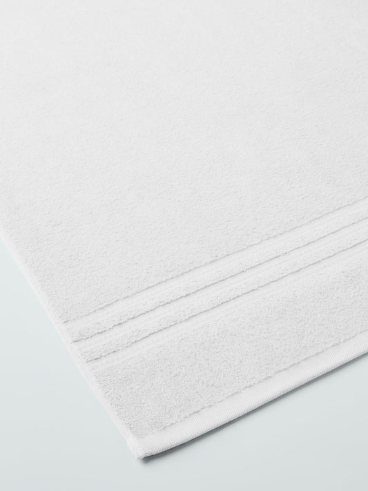 plush, folded bath sheets in a warm, inviting "Signature White" color. The towels have a thick, textured weave and subtle stripes - {{Signature White}}