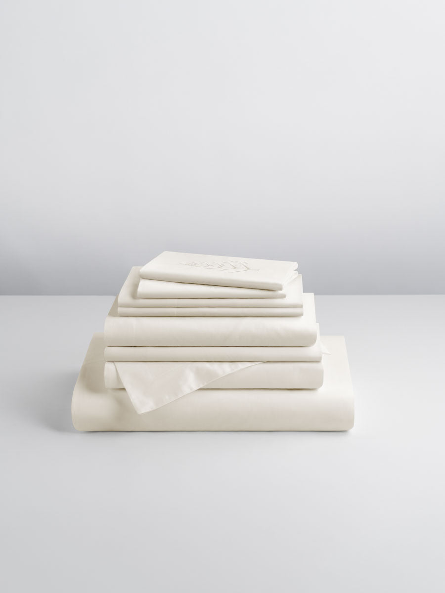 A set of Signature Whitel-colored sheets, folded into perfect rectangles and stacked on a flat surface.