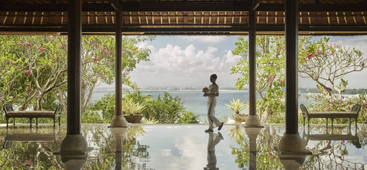 Person walking by a pool with a scenic view of trees and water