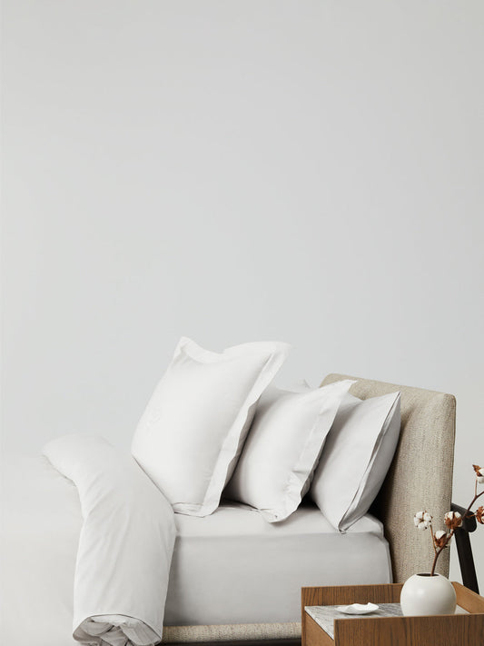 Side angle of a bed made up with Four Seasons Signature Linens in Signature White.{{Signature White}}