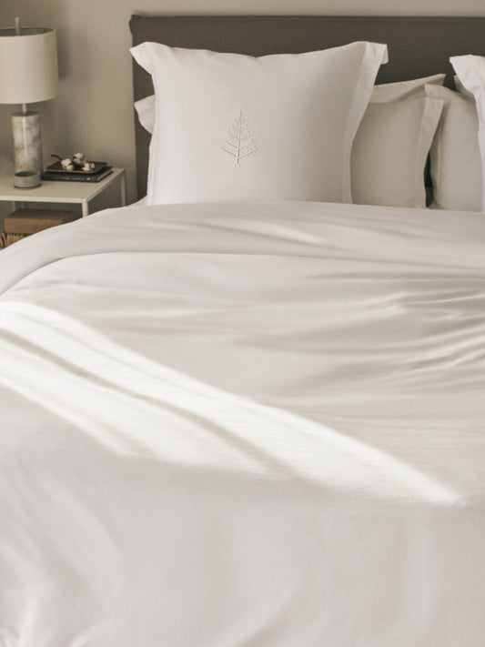 A made bed with a white down alternative duvet and matching pillows.