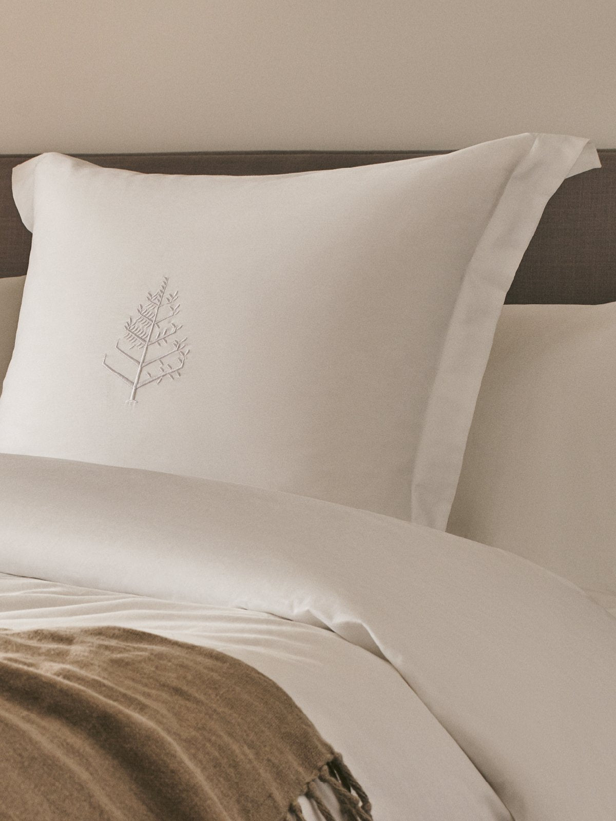 A soft, white, rectangular pillow rests on a bed