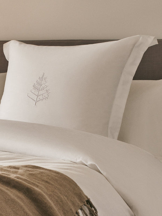 A soft, white, rectangular pillow rests on a bed