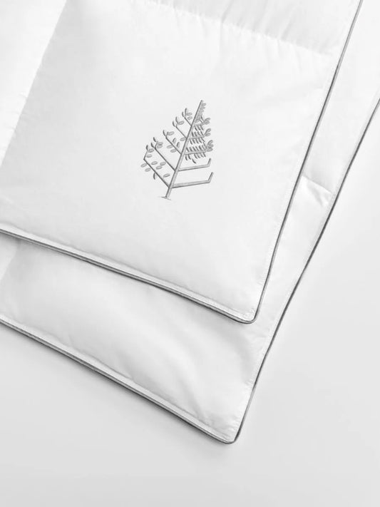 Corner of a white duvet with a Four Seasons embroidered logo. 