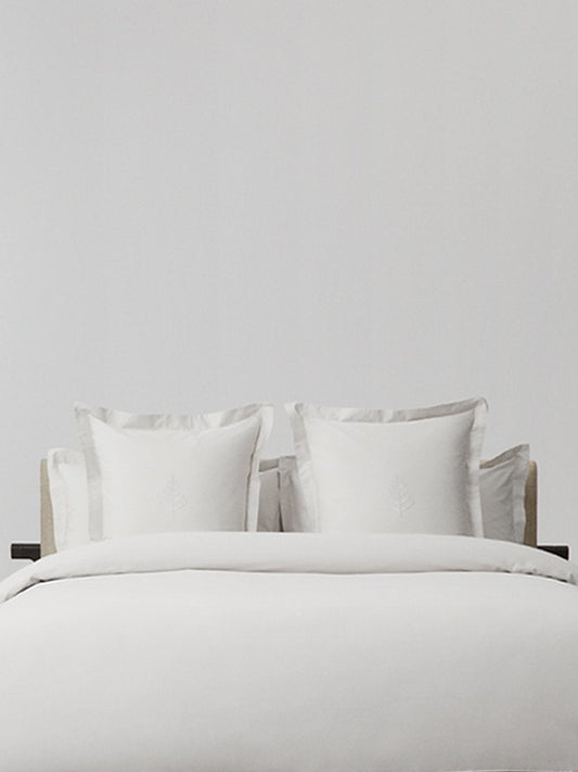 White pillows with decorative embroidery on a duvet, placed on top of a luxury bed.