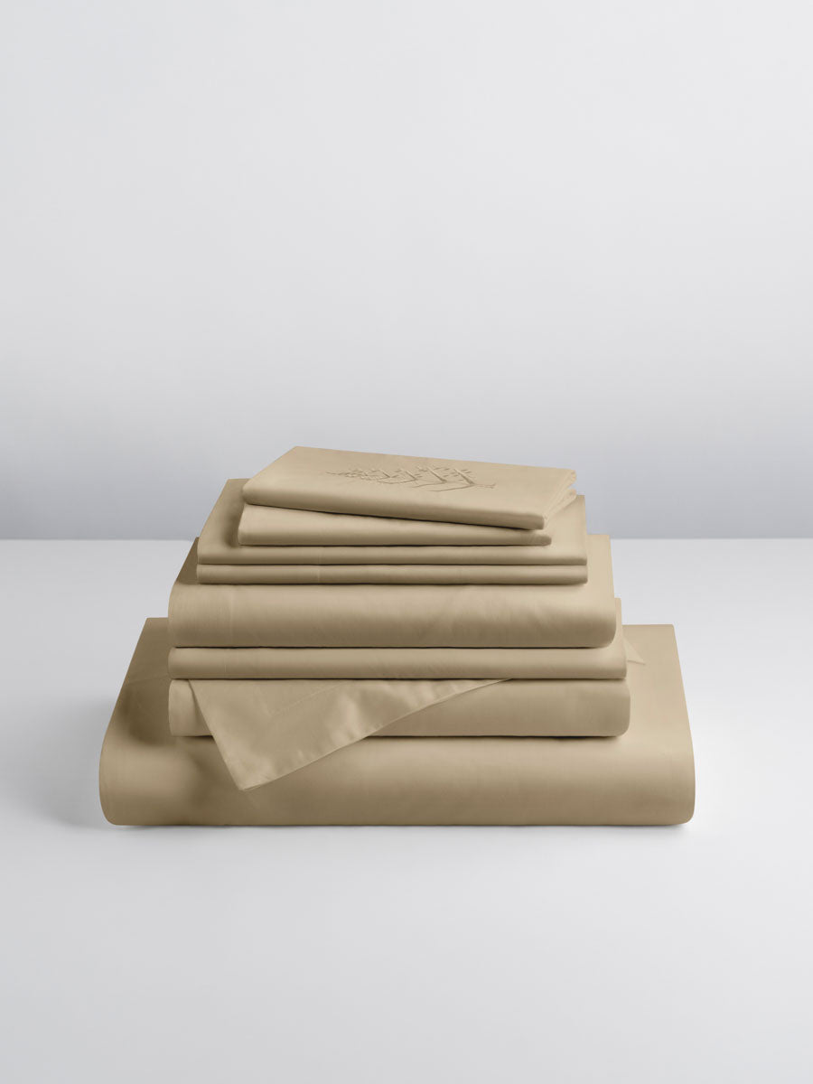 A set of Egyptian Camel-colored sheets, folded into perfect rectangles and stacked on a flat surface.