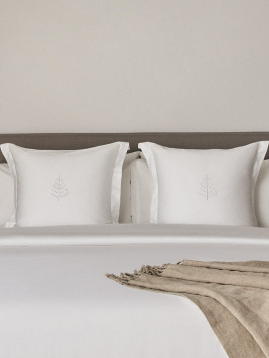 Two white square pillows with the store logo carefully embroidered.