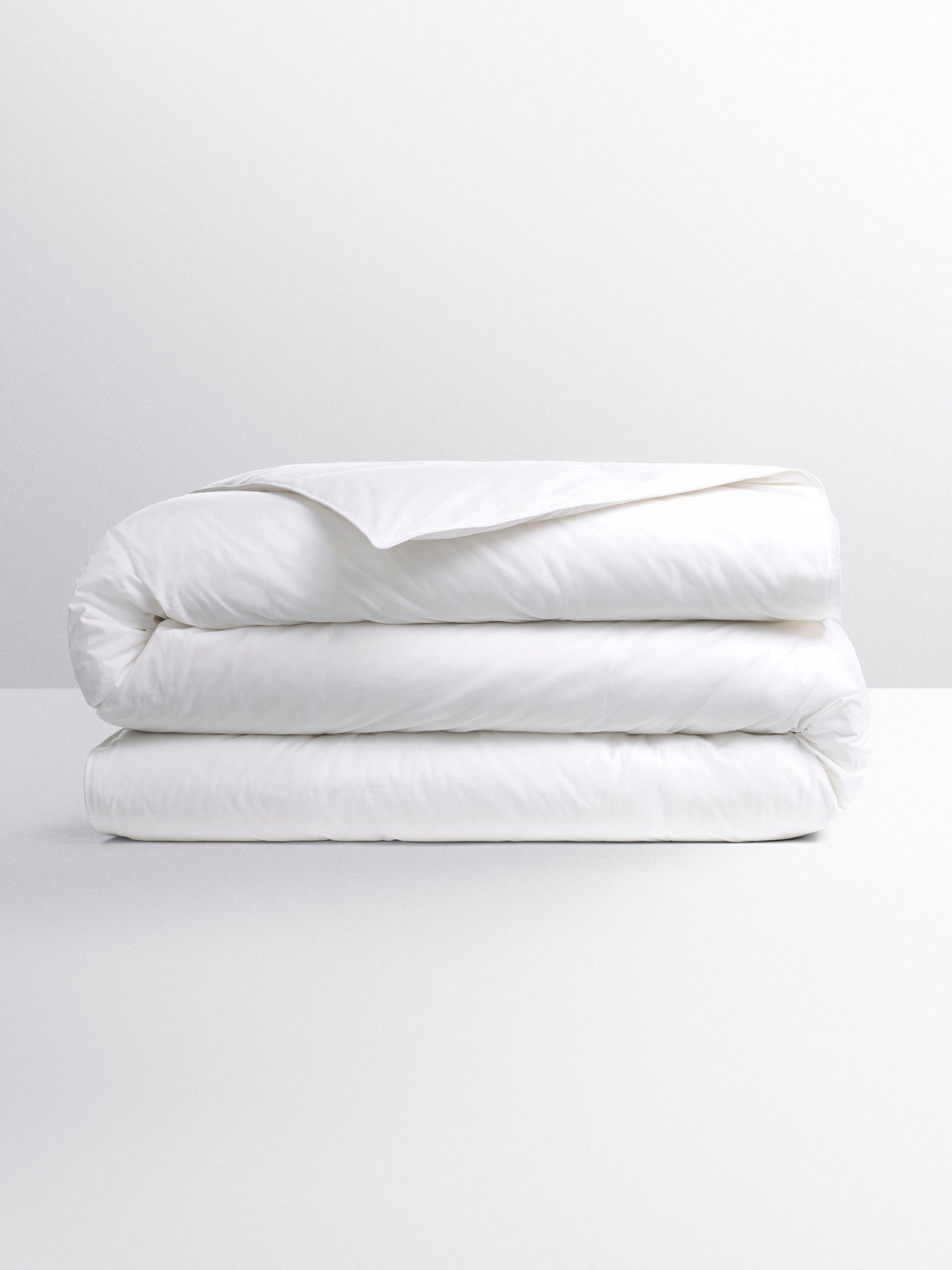 White duvet, with a soft and uniform texture, folded neatly on a light surface