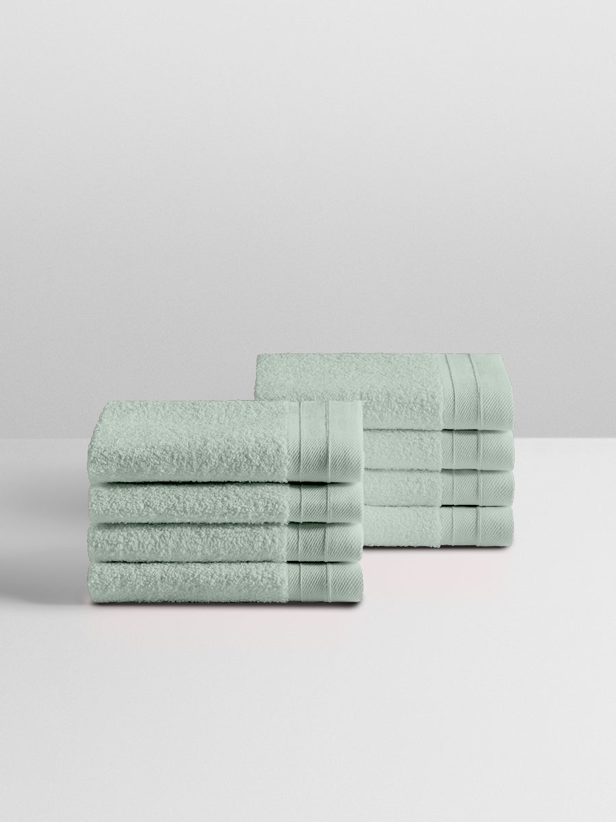 A stack of eight soft, “Florentine Sage” colored clothes neatly folded on a white surface. - {{Florentine Sage}}