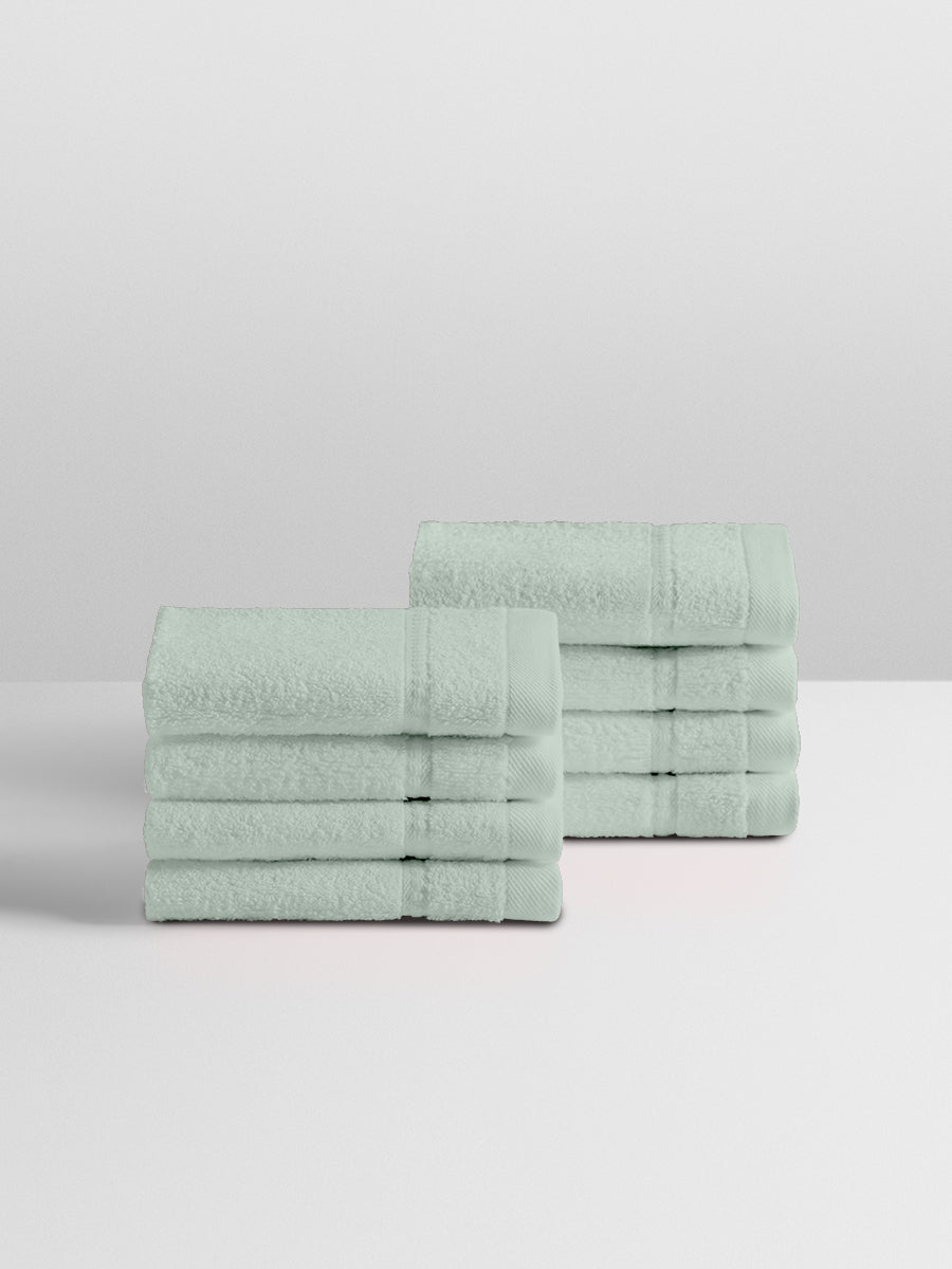 A stack of eight soft, “Florentine Sage” colored clothes neatly folded on a white surface. - {{Florentine Sage}}