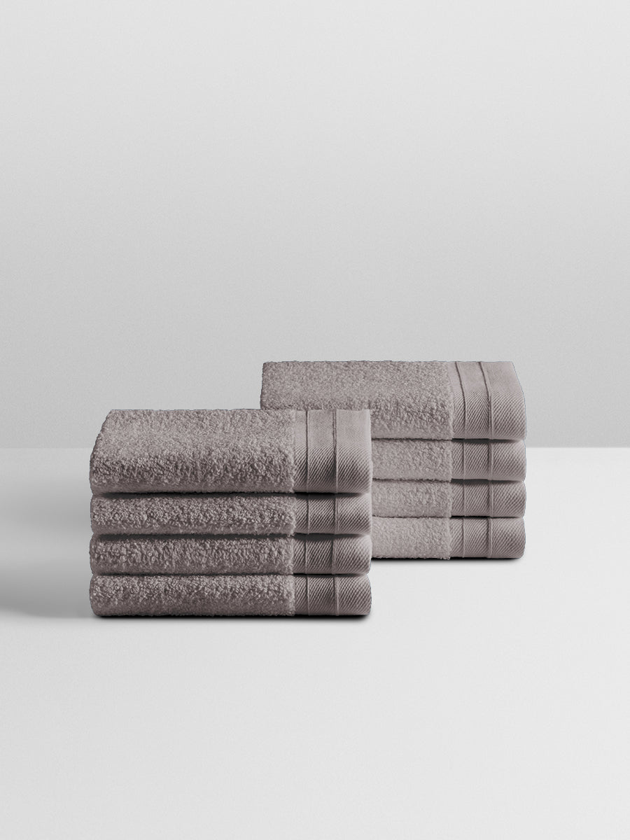 A stack of eight soft, “Hampshire Charcoal” colored bath wash clothes neatly folded on a white surface. - {{Hampshire Charcoal}}