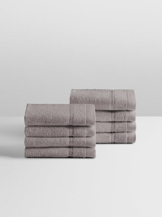 A stack of eight soft, “Hampshire Charcoal” colored bath wash clothes neatly folded on a white surface. - {{Hampshire Charcoal}}